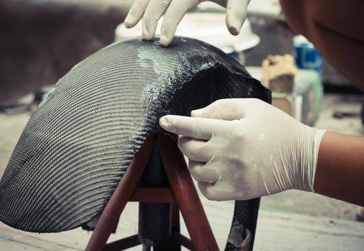 A worker completes a composite layup for a small sized complex geometry.