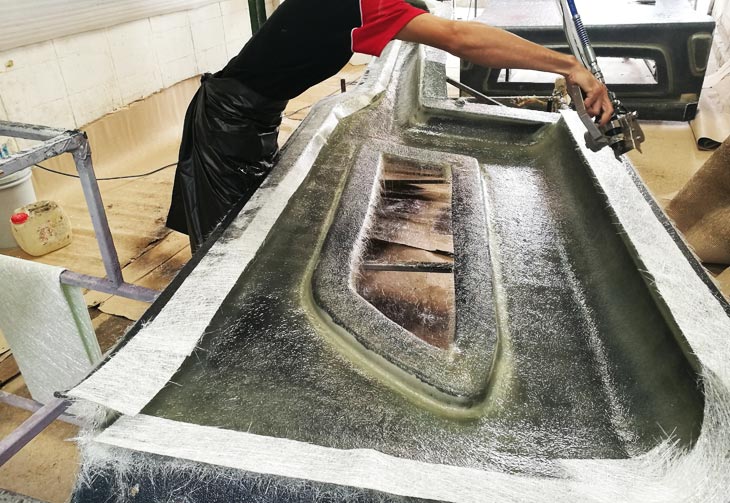 Fig. 03: A worker sprays chopped fiberglass into the resin stream for fast composite construction.