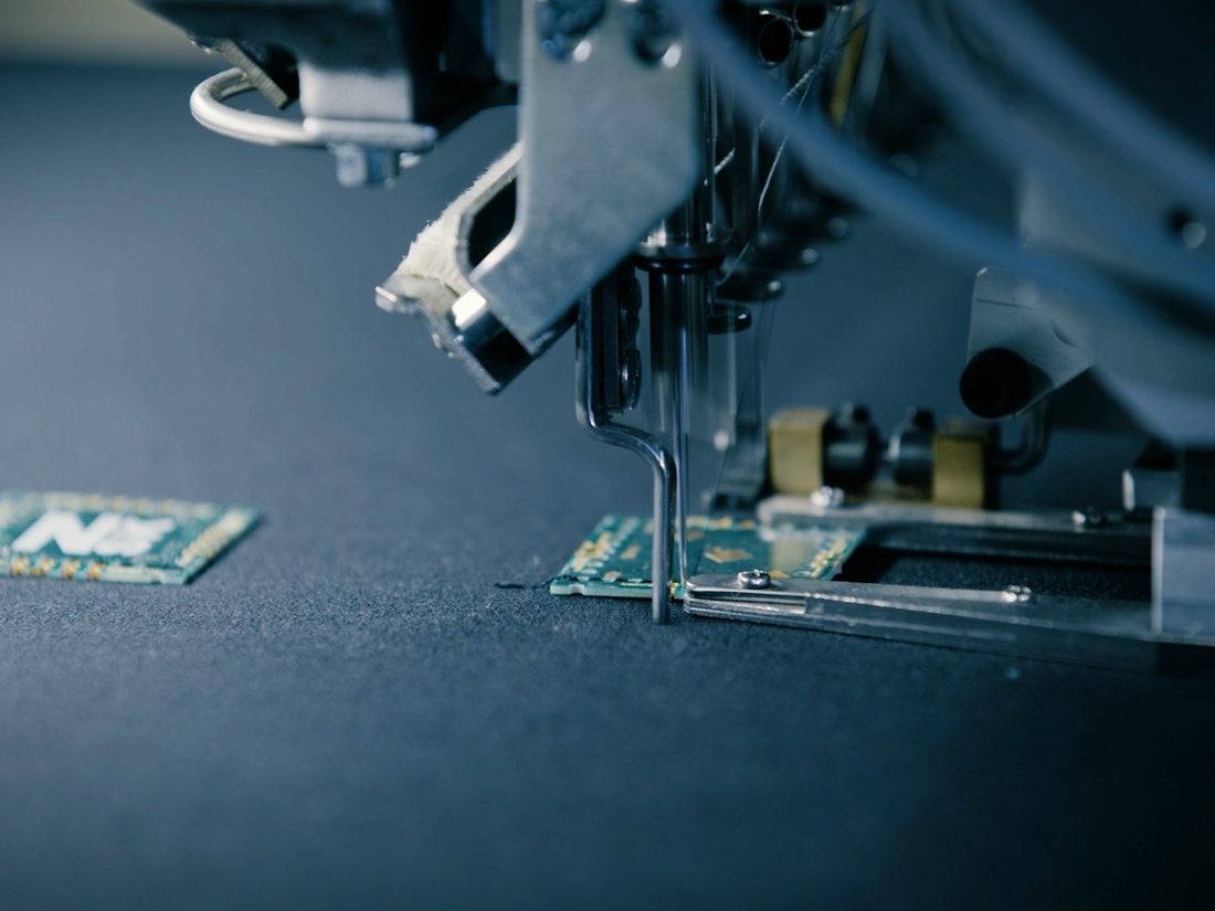 Nahaufnahme eines starren PCB-Trägers bei der Platzierung und Kontaktierung auf einem textilen Trägermaterial
